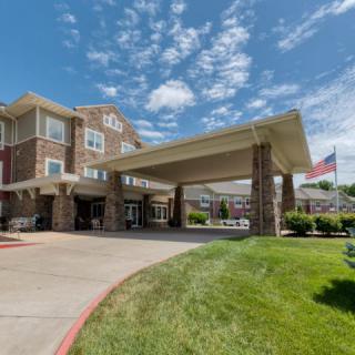 A modern building entrance with a covered driveway and an American flag.