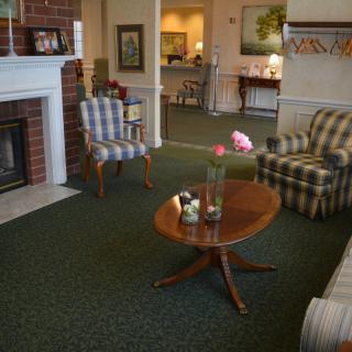 A cozy living room with a fireplace, armchairs, and a wooden coffee table.