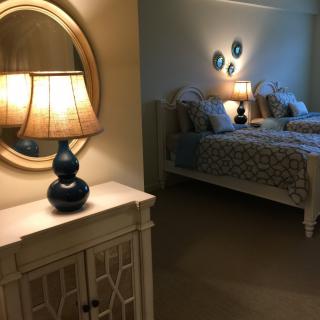 A cozy bedroom featuring a softly lit lamp, twin beds, and a decorative mirror.