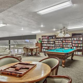A cozy game room with a billiards table and bookshelves filled with books.
