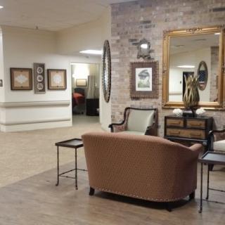 A cozy lobby featuring a seating area with a sofa, tables, and decorative artwork.