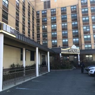 A view of the exterior of a hotel featuring a multi-story building with a parking area in front.