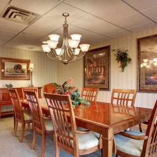 A well-furnished dining room with a large wooden table, surrounding chairs, and a chandelier.
