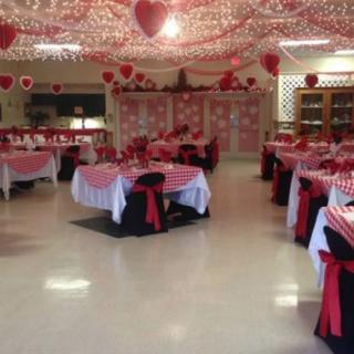 A dining area beautifully decorated with a Valentines Day theme, featuring red and white table settings and heart decorations.