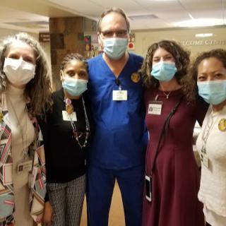 A group of healthcare professionals posing together in a hospital setting, all wearing masks.