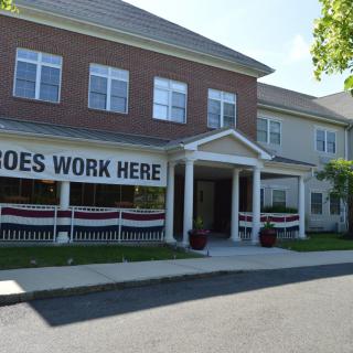 A two-story building with a large banner reading 'HEROES WORK HERE' displayed near the entrance.