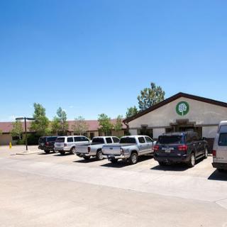 A clear sunny day showcasing a parking lot filled with various vehicles next to a building.