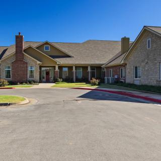 A suburban residential building with a circular driveway under a clear blue sky.