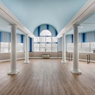 A bright and spacious interior featuring elegant columns and large windows, perfect for gatherings or events.