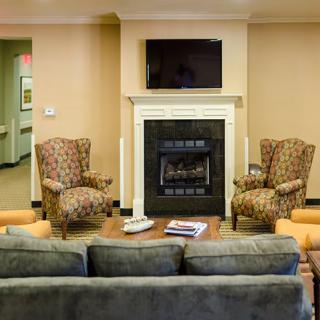 A cozy living room with a fireplace, armchairs, and a sofa facing a mounted television.