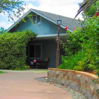 A charming house with lush greenery and a neatly paved driveway.