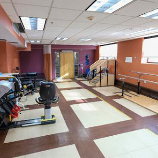 A spacious physical therapy room equipped with exercise equipment and balance bars, designed to facilitate rehabilitation.