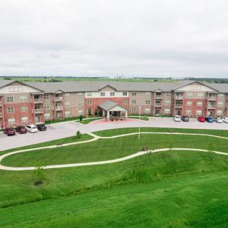 An aerial view of a residential apartment complex with landscaped greenery and a parking area.