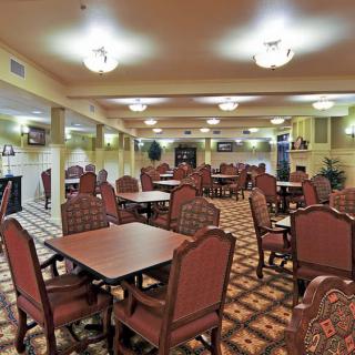 A spacious dining area with elegantly arranged tables and chairs, illuminated by ceiling lights.