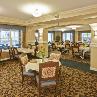 A spacious dining room with elegantly arranged tables and chairs, featuring a warm and inviting decor.