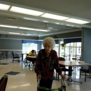 An elderly person using a walker in a dining area.