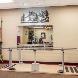 An interior view of a physical therapy room with handrails and a mirror for rehabilitation exercises.
