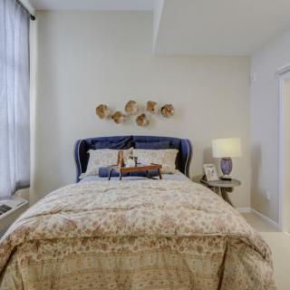A cozy bedroom with a plush bed, decorative wall art, and a bedside lamp.