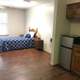 A cozy studio apartment with a bed and a small kitchenette.