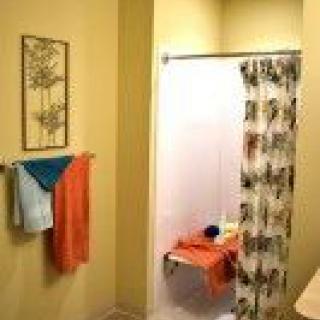 A cozy bathroom with colorful towels and a patterned shower curtain.