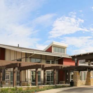 A modern architectural building with a wooden pergola and a clear sky in the background.