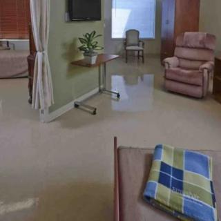 A well-furnished hospital room with a bed, reclining chair, and a small table.