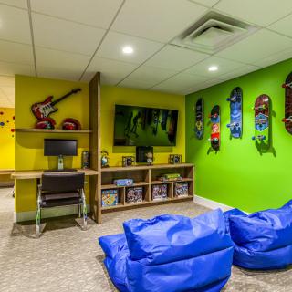 A vibrant gaming room with bean bags, skateboards on the wall, and a central TV setup.
