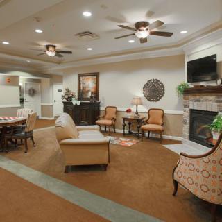 A cozy living room with elegant furnishings, featuring a fireplace, ceiling fans, and comfortable seating.