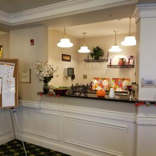 A reception area with a counter, decorative flowers, and overhead lighting.