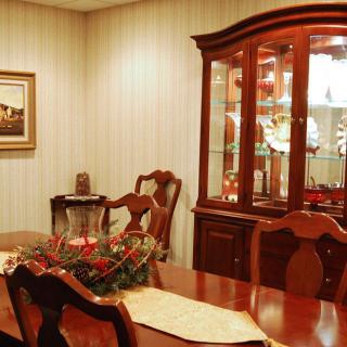 A traditional dining room with a wooden table, chairs, and a china cabinet displaying glassware.