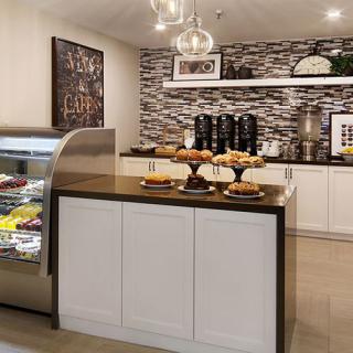 A modern cafe interior with a dessert display and coffee station.