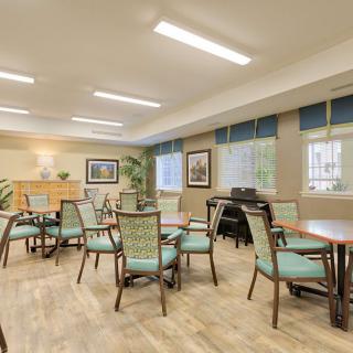 A well-lit room with multiple chairs and tables, featuring large windows and tasteful decor.