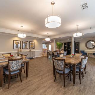 A modern dining area with neatly arranged tables and chairs, featuring elegant lighting and a wooden floor.