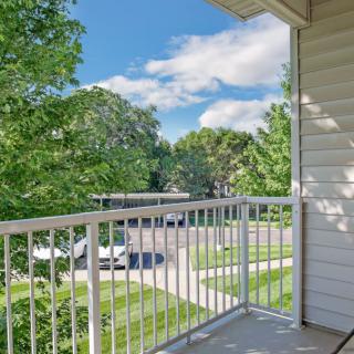 A view from a balcony overlooking a suburban neighborhood with trees and clear skies.