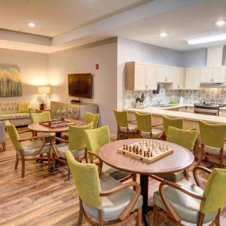 A modern communal space featuring a kitchen, living area, and tables with chess boards.