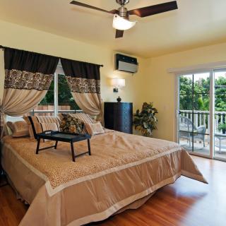 A cozy bedroom with a large bed, ceiling fan, and sliding doors leading to a balcony.