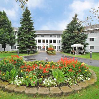 A beautiful garden area in front of a residential building, featuring colorful flowers and well-maintained landscaping.