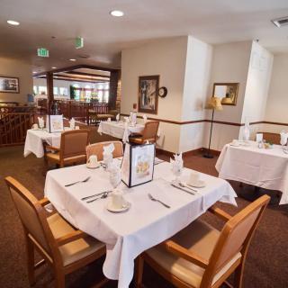 A well-arranged dining area with tables set with white tablecloths and neatly organized tableware.