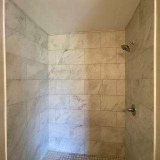 A minimalist shower with marble-like tiles.