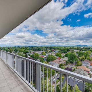 A scenic view from a balcony overlooking a sprawling cityscape under partly cloudy skies.