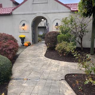 A charming garden pathway leading to a welcoming entrance, adorned with seasonal pumpkins.