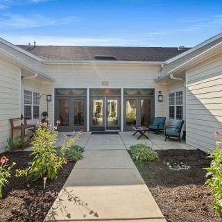 A serene courtyard with outdoor seating and a garden, surrounded by a residential building.