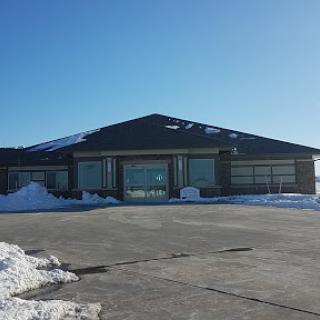 A modern building surrounded by snow, under a clear blue sky.