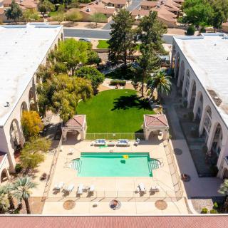 Aerial view of a courtyard featuring a swimming pool, lawn, and surrounding buildings.