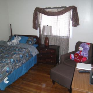 A cozy bedroom with a bed, chair, lamp, and window with curtains.