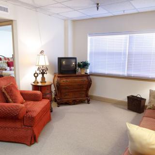 A cozy living room with an armchair, TV, lamp, and window.