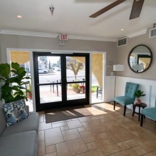 A cozy lobby area with seating, plants, and a mirror near the entrance.