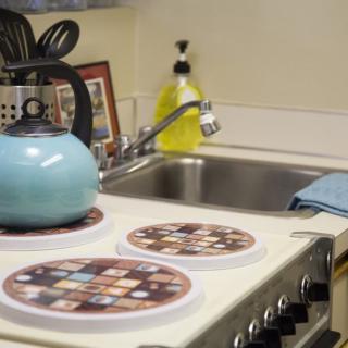 A cozy kitchen corner with a blue teapot on the stovetop and utensils by the sink.