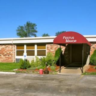 Entrance of a building with a red awning labeled 'Manor' and surrounding landscaping.