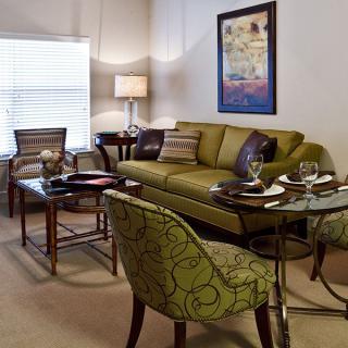 A cozy living room with a green sofa, patterned chairs, and elegant decor.